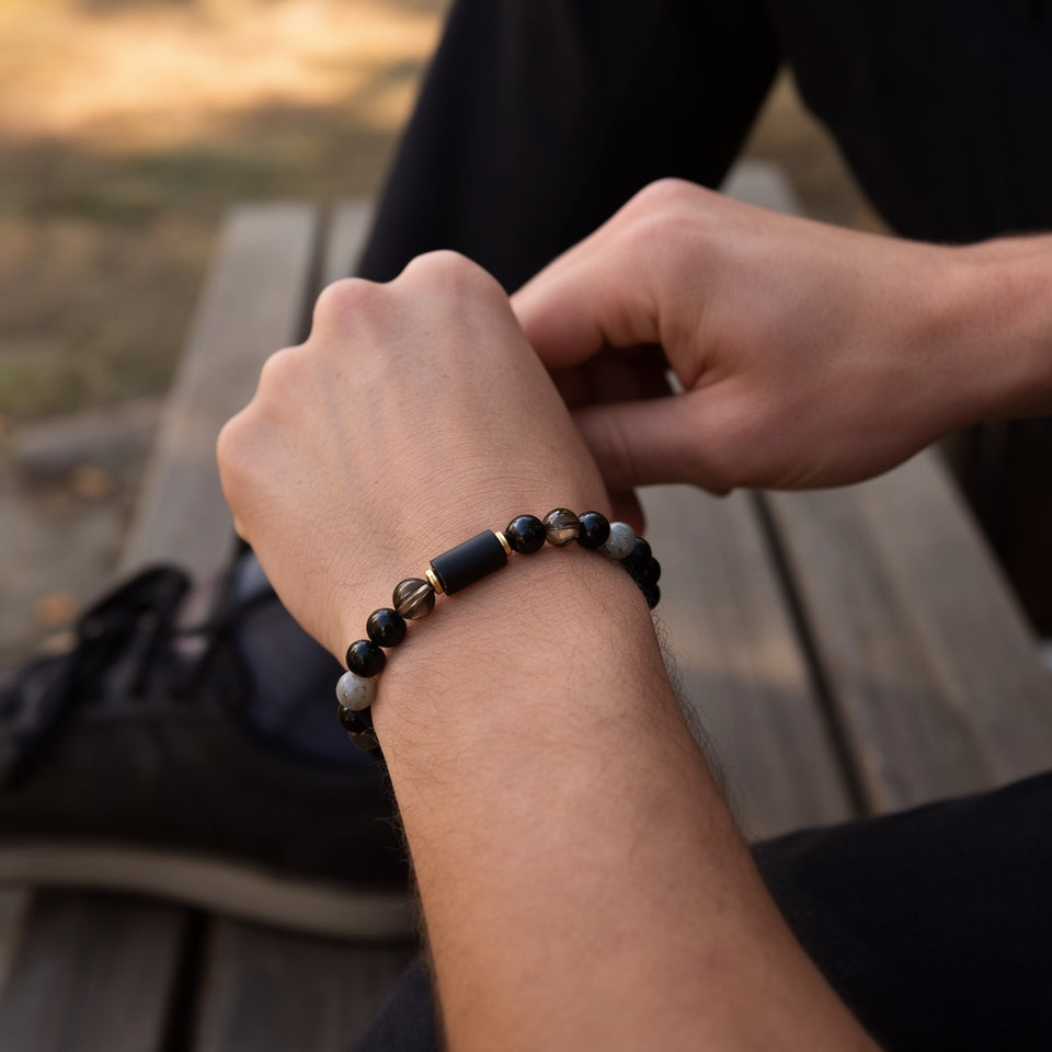 Numero 7 bracelet on a man's wrist as he sits on a bench beside a shoe