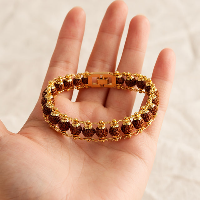 Gold plated 5 mukhi rudraksha bracelet resting on an open palm for size reference