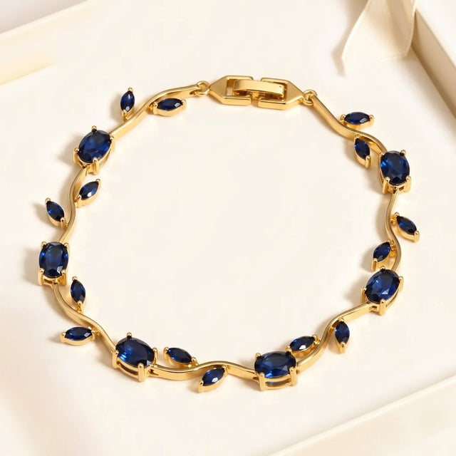 Gold tone tulip bracelet with blue stones in a cream gift box