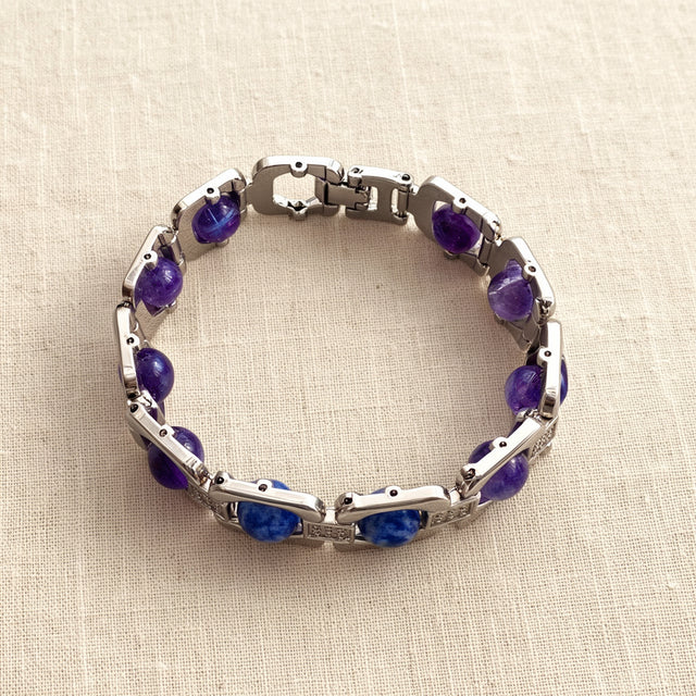 Silver Aquarius zodiac bracelet laid flat on cream linen