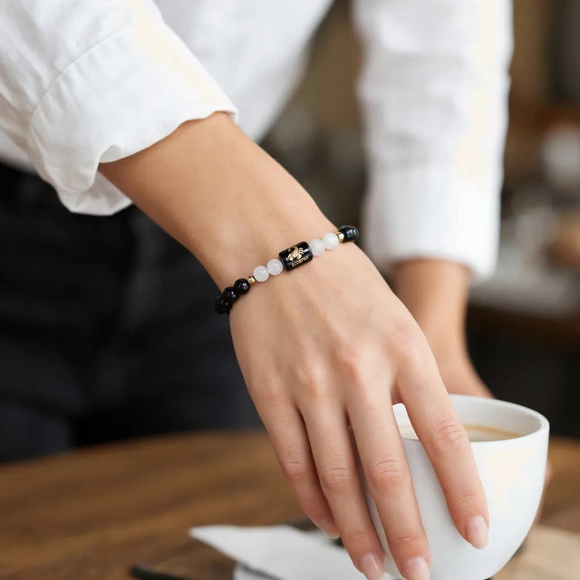 Scorpio zodiac bracelet on a woman's wrist with a coffee cup