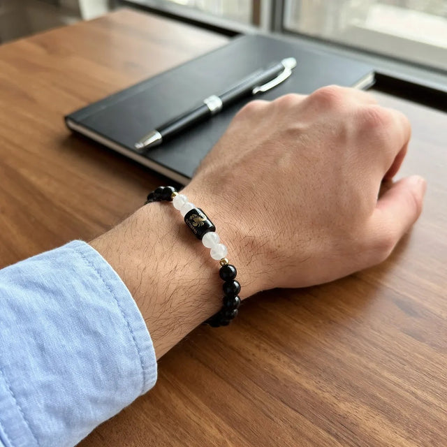 Scorpio zodiac bracelet on a man's wrist at a desk