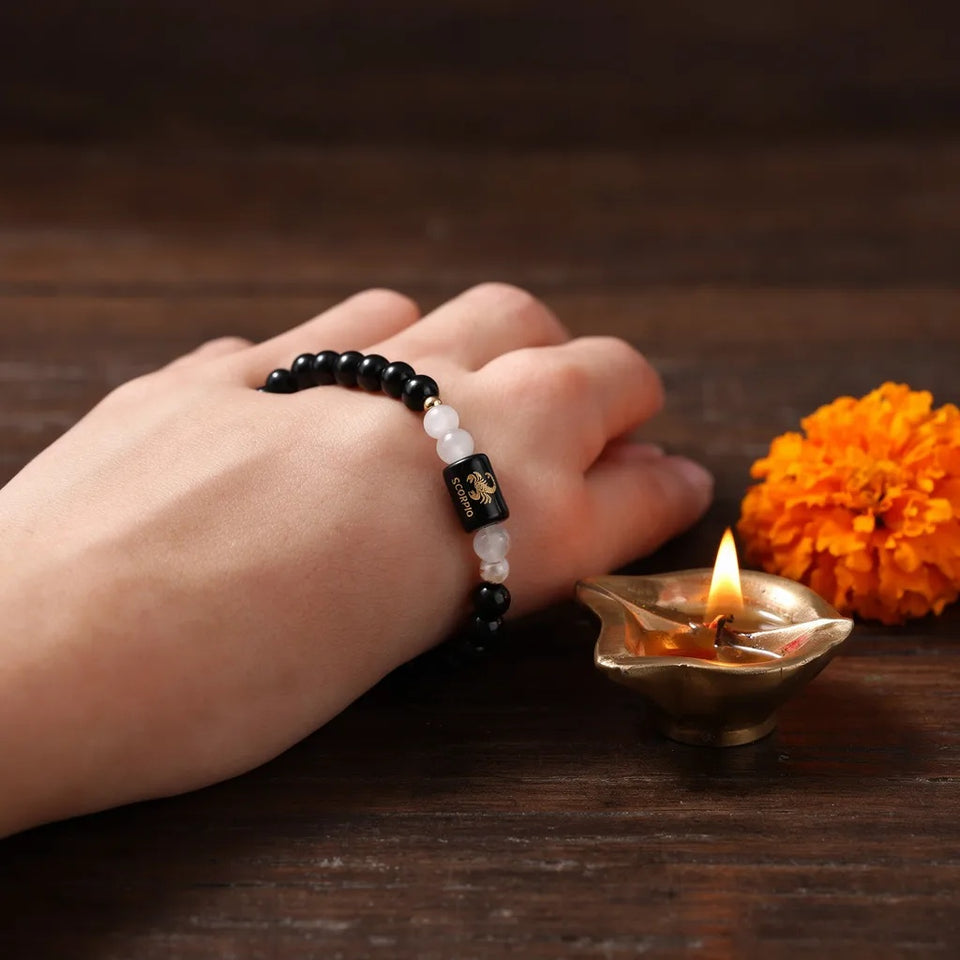 Scorpio zodiac bracelet worn beside a diya and marigold
