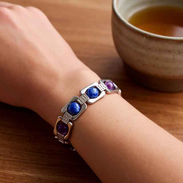 Silver Aquarius zodiac bracelet worn at a desk with a cup of tea