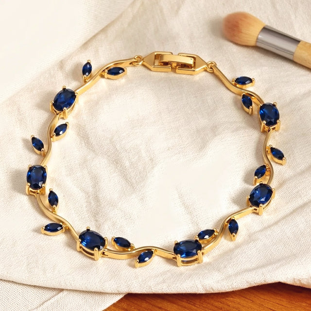 Gold tone tulip bracelet with blue stones resting on a dry cream cotton cloth