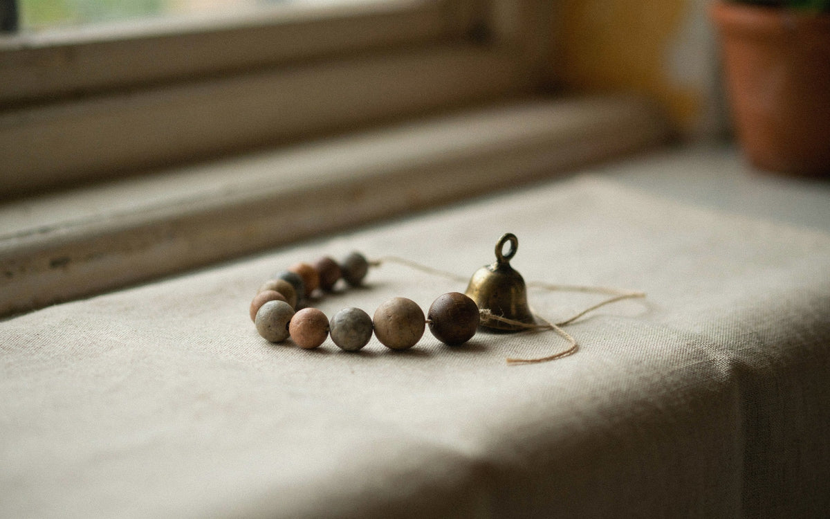 Nine round stone beads laid in a loose arc on cream linen
