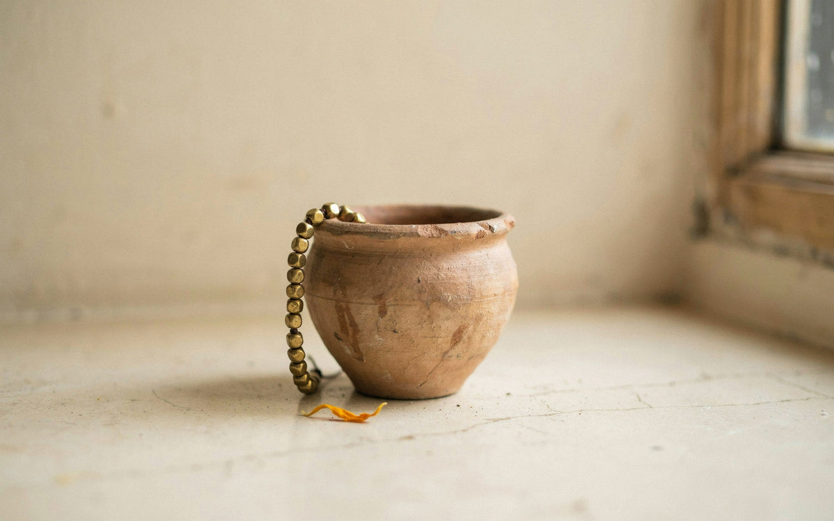 A golden pyrite bead bracelet draped over the rim of a small