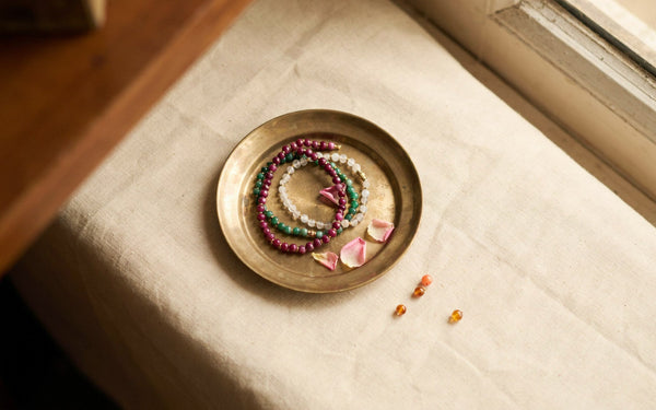 Colourful gemstone bracelets resting in a small brass plate