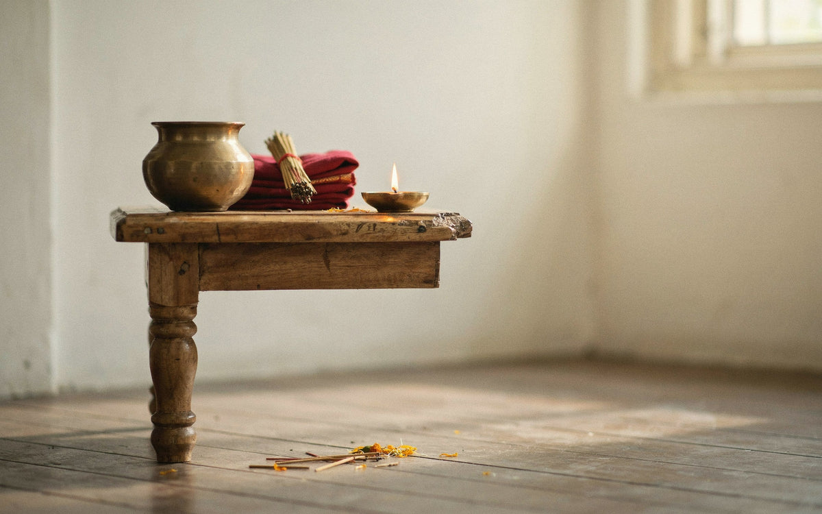 A low wooden puja chowki with a brass lota
