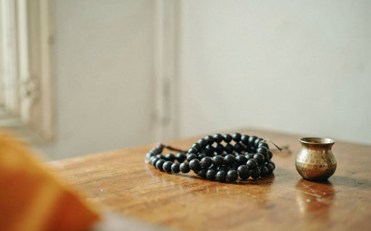 Black karungali ebony mala coiled beside a brass lota