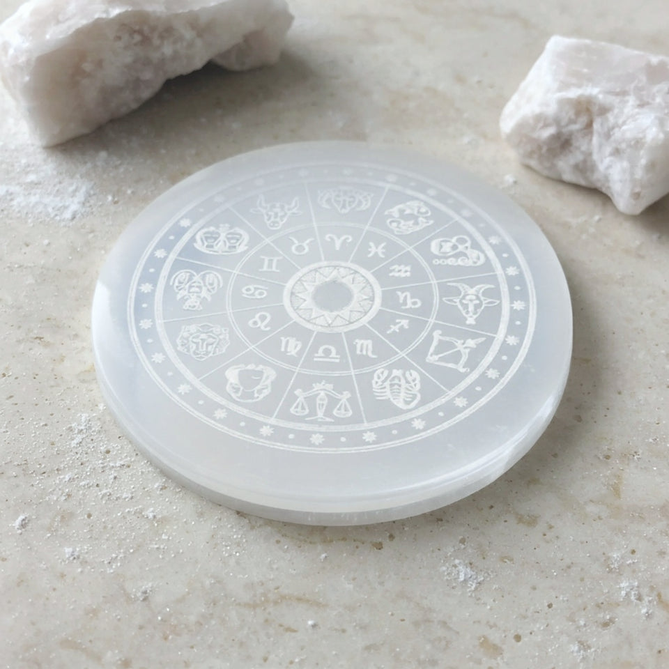 Selenite charging plate on a stone worktable with raw white selenite rough blocks