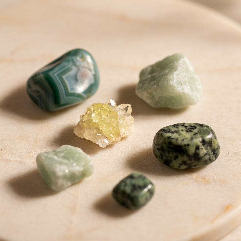 Raw rough green agate, aventurine, quartz and jasper stones on a cream stone surface