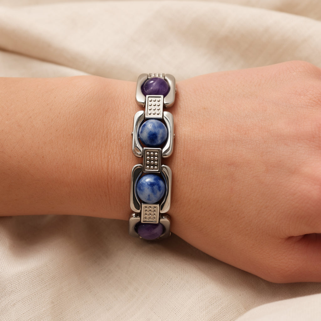 Silver Aquarius zodiac bracelet on a woman's wrist resting on cream cloth
