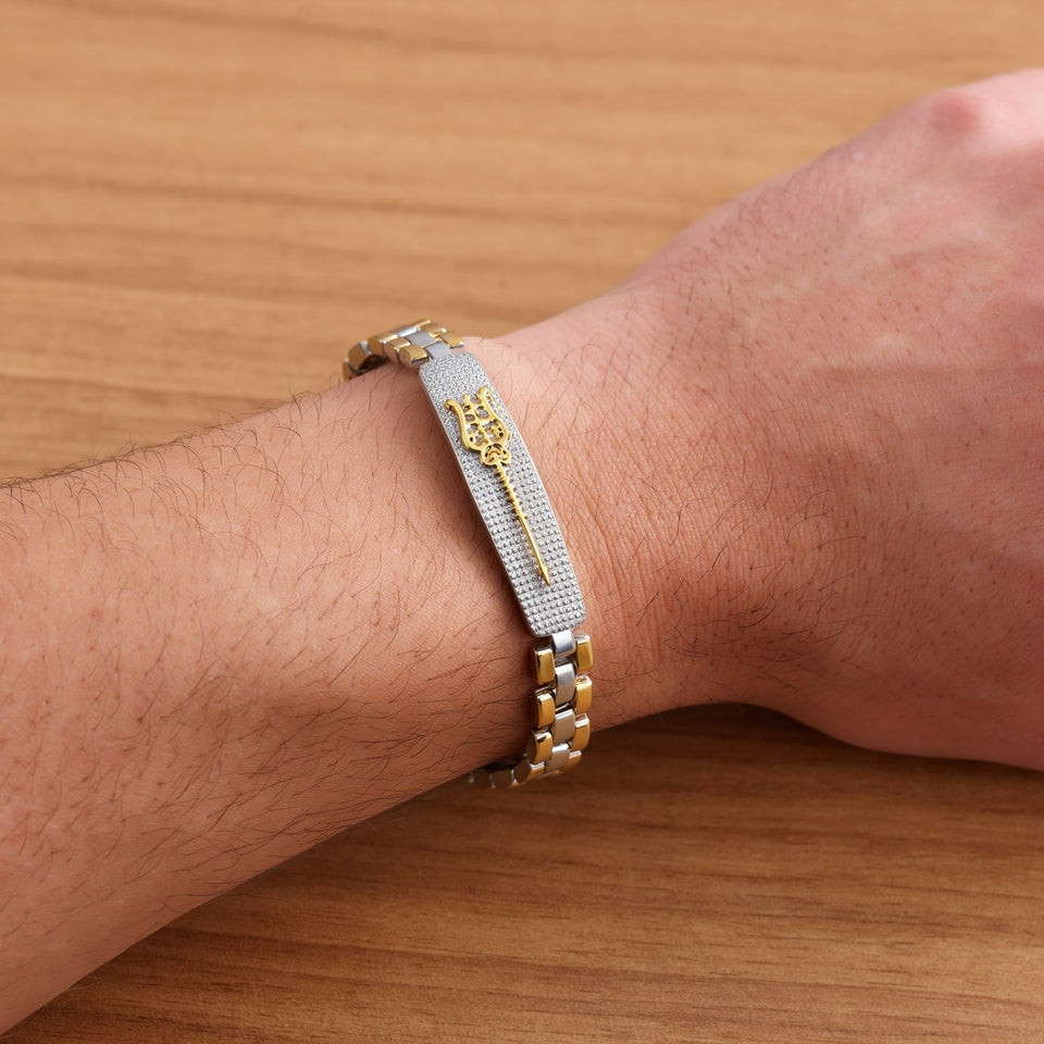 Shiva's Trishul dual tone bracelet on a man's wrist resting on an oak table