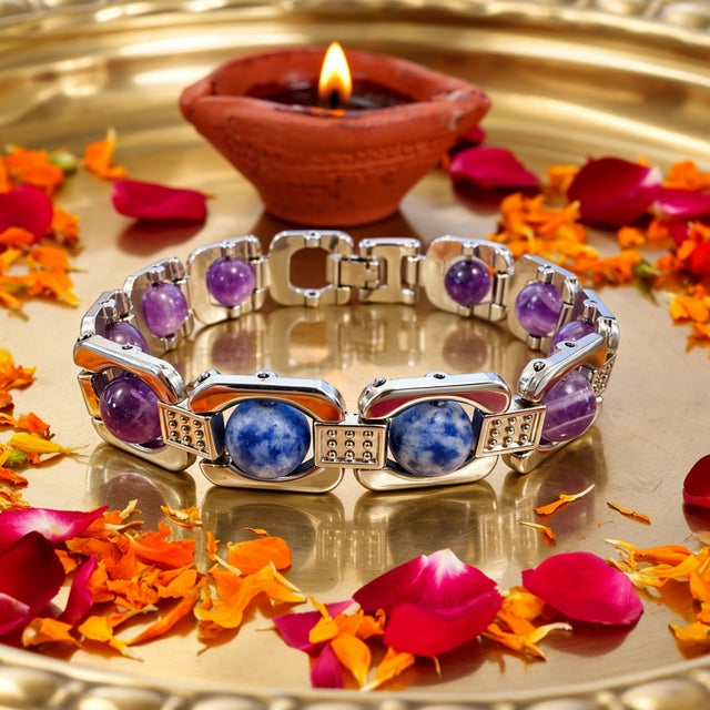 Silver Aquarius zodiac bracelet on a brass tray with flower petals and a diya