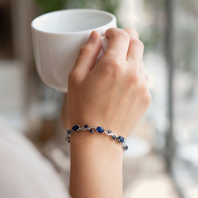 Hand holding a coffee cup wearing a blue tulip bracelet