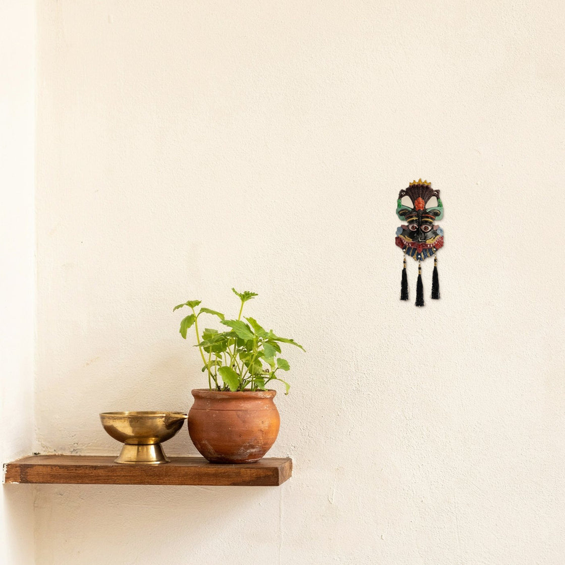 nazar suraksha ritual kirtimukh at a wall beside a small plant on a shelf