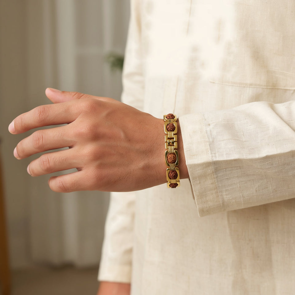 Man in a cream kurta wearing a gold link Rudraksha bracelet on his wrist