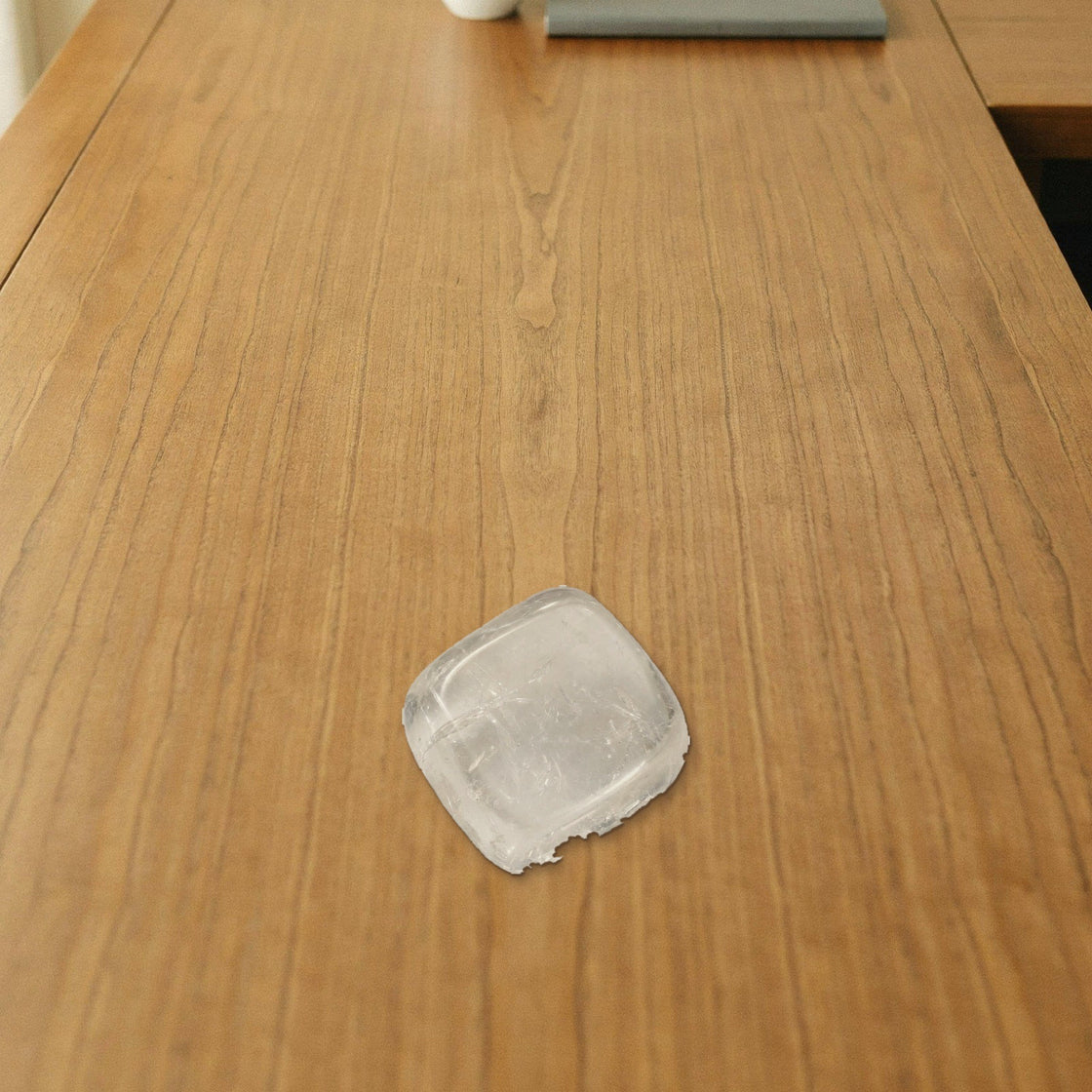 clear quartz tumble placed on a wooden desk