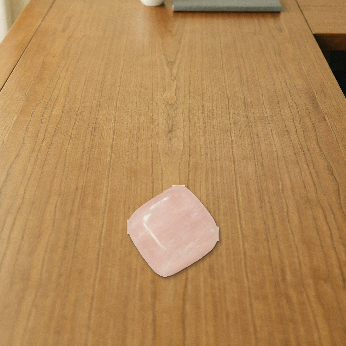 rose quartz love attraction tumble placed on a wooden desk