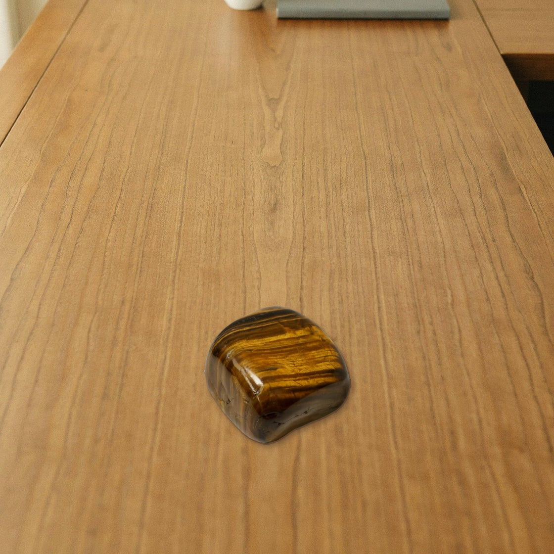 tiger eye tumble placed on a wooden desk