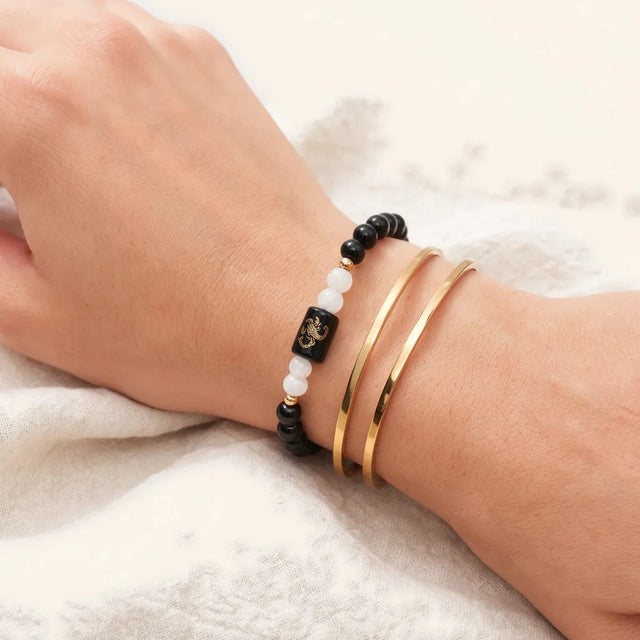 Scorpio zodiac bracelet worn with thin gold bangles