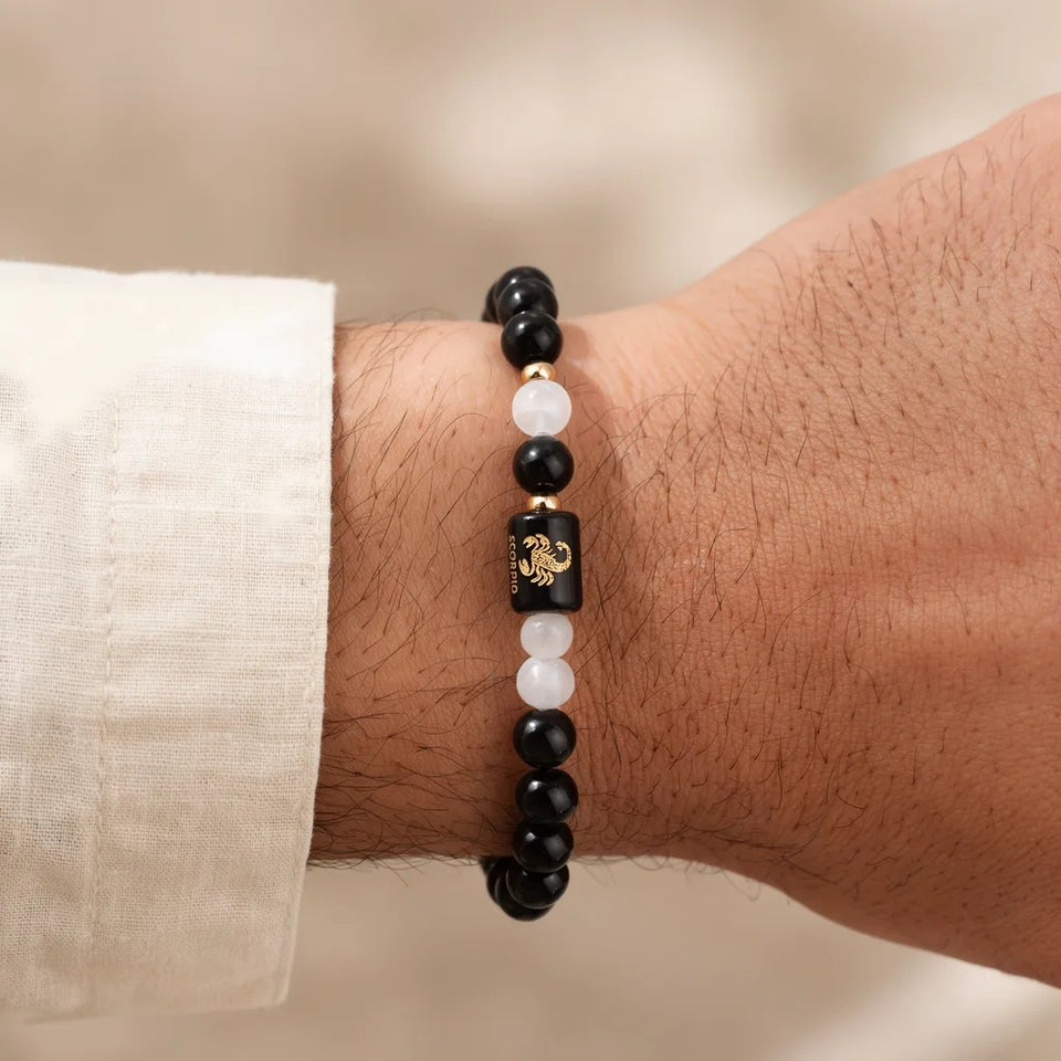 Scorpio zodiac bracelet on a man's wrist with a cream kurta
