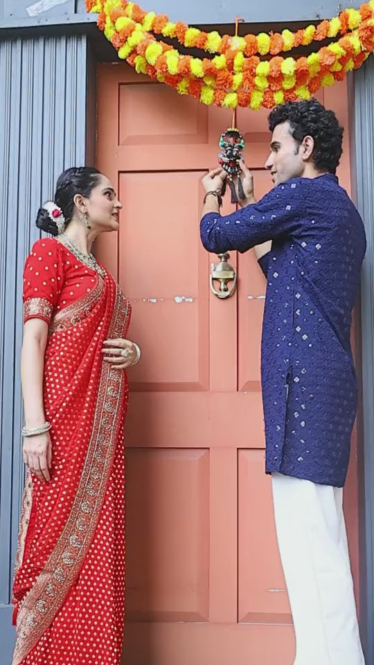 Couple hanging a Kirtimukh on a marigold-decorated main door