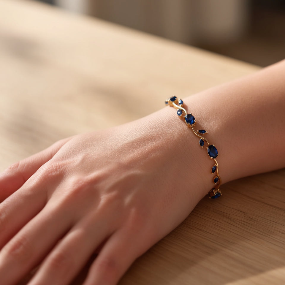 Gold tone tulip bracelet with blue stones worn on the wrist