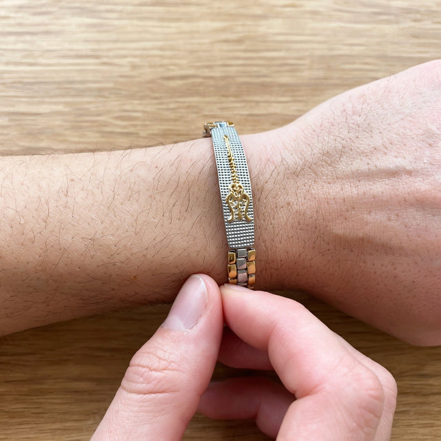 Fingers closing the clasp of a dual tone Trishul bracelet on the wrist